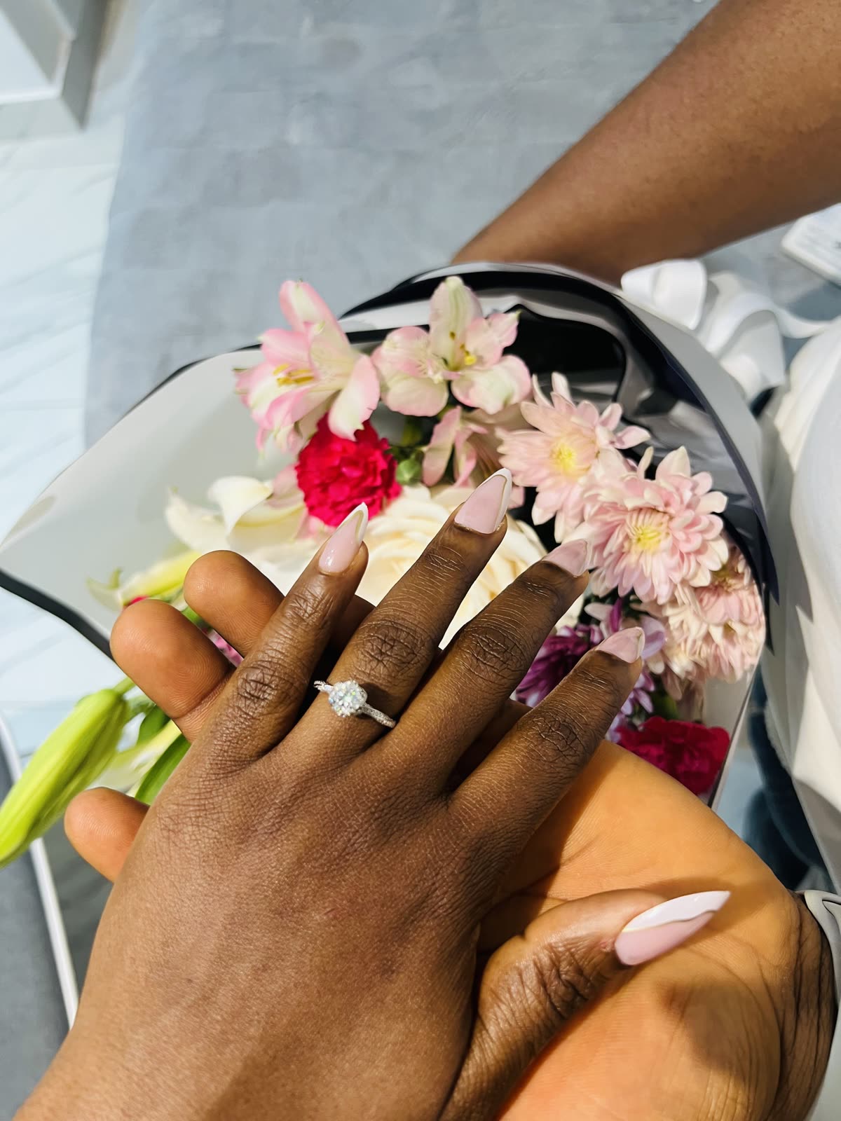 The ring, hands intertwined over the bouquet